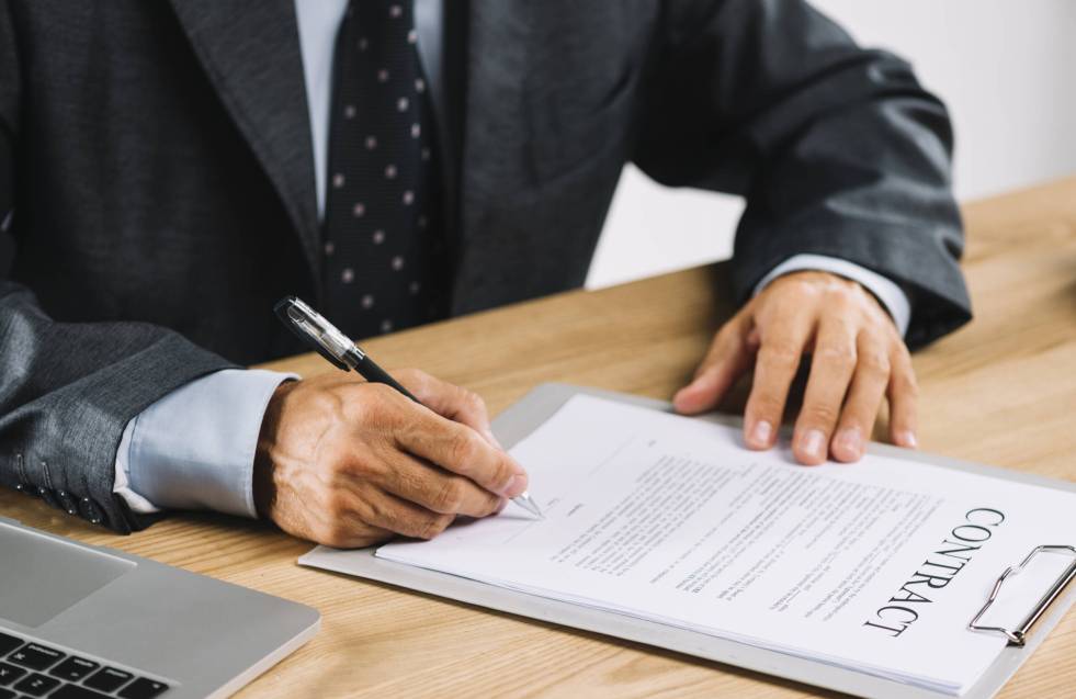 male-lawyer-signing-contract-with-pen-clipboard
